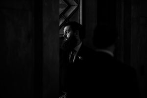wedding photo black and white of bearded man illuminated by a narrow door.
