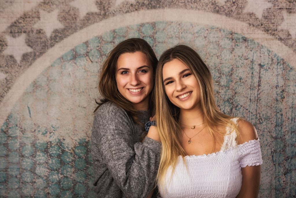 senior and sister against patterned wall